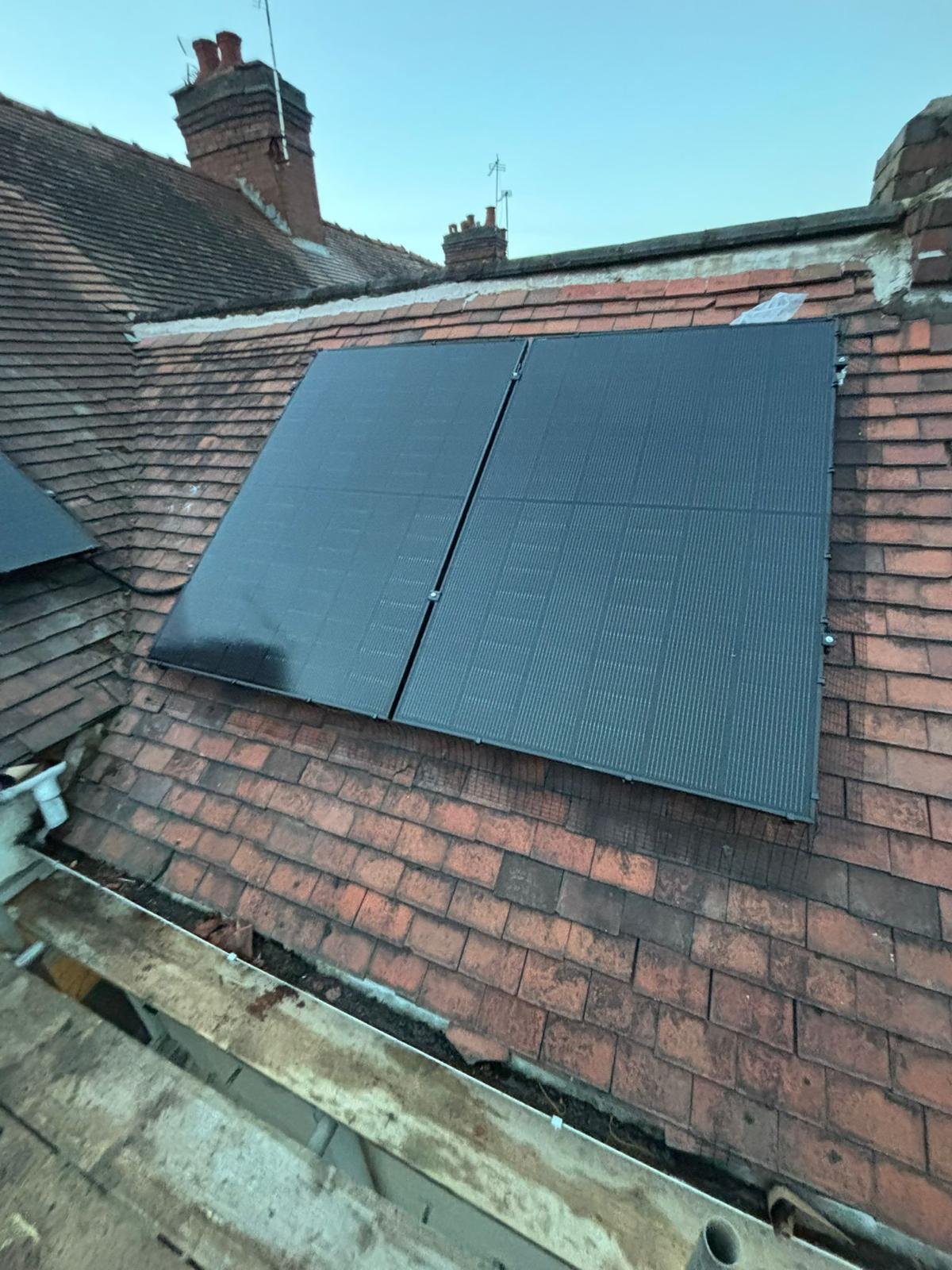 Compact two-panel solar array on a steep red tiled roof