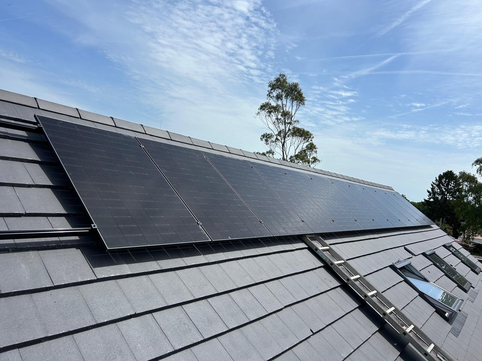 Long row of black solar panels on a grey slate-style roof in Hampshire