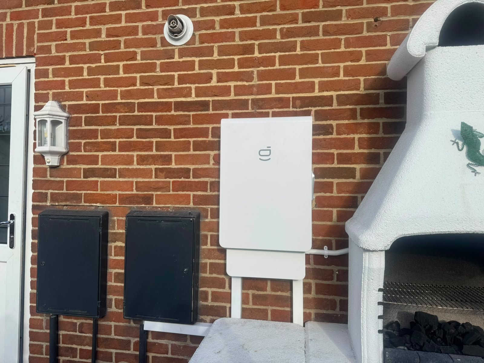 Solar inverter installed on a red brick exterior wall in Hampshire