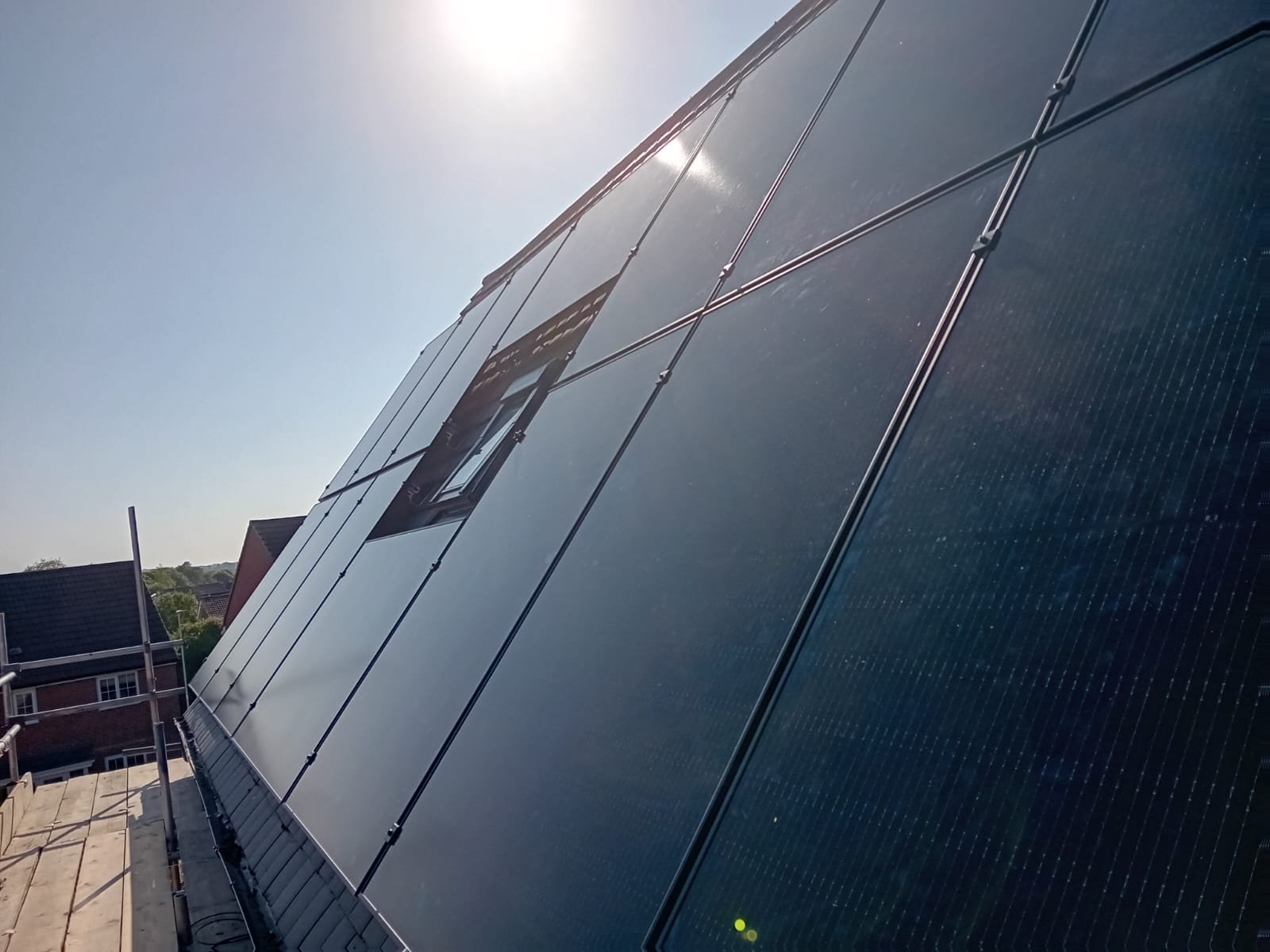 Close-up of black solar panels reflecting sunlight on a Hampshire house roof