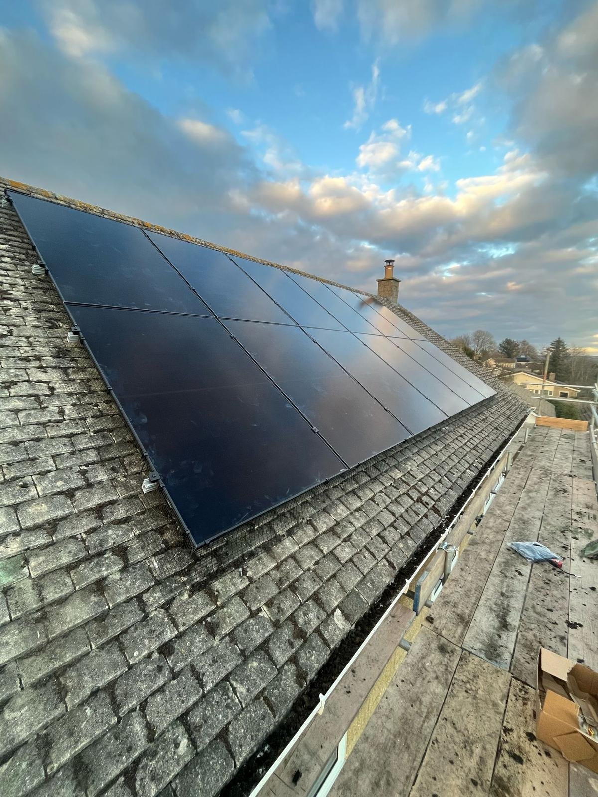 Sleek all-black solar PV array installed on a slate roof in Winchester at dusk