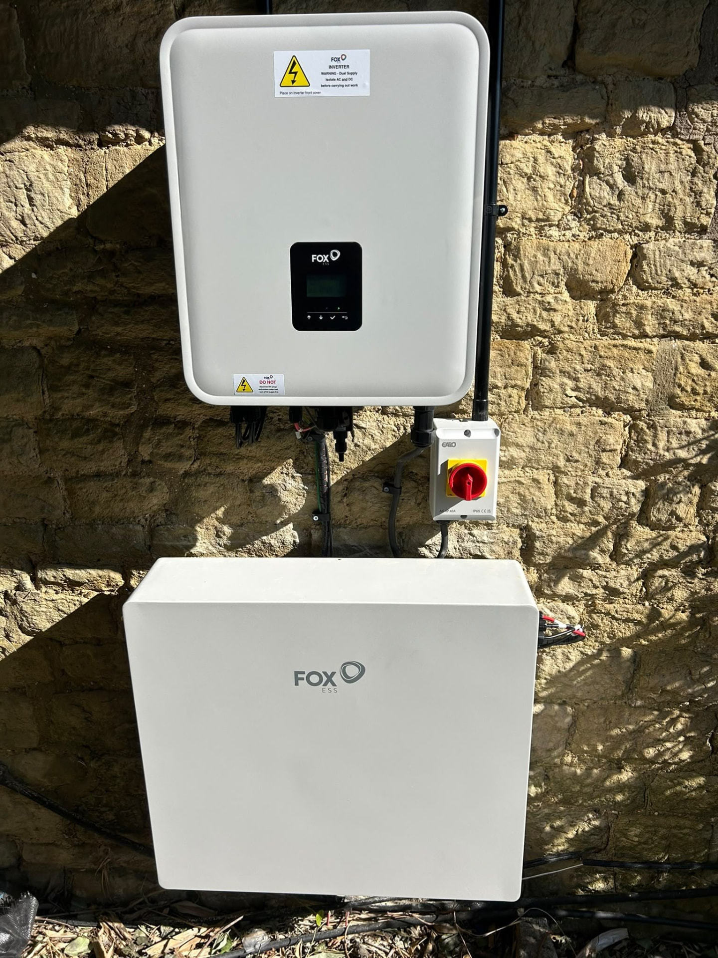 Fox ESS inverter and battery mounted on a stone masonry wall in Hampshire