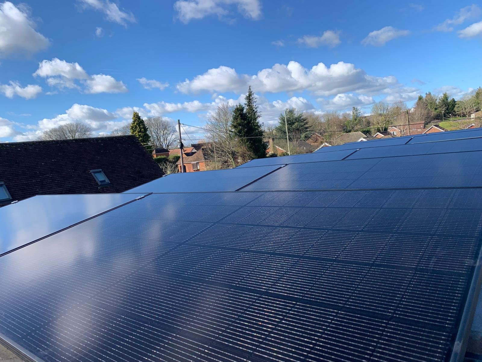 Wide view across a suburban rooftop solar PV array under blue sky